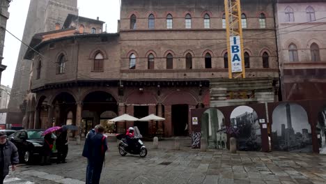 Public-Articulated-Bus-Driving-Past-In-Bologna-Along-Piazza-della-Mercanzia,-5-On-Rainy-Day