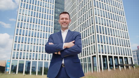 Caucasian-business-man-in-suit-poses-and-smiles-in-front-of-skyscraper