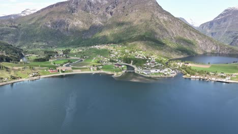 Idyllic-Skjolden-in-the-end-of-Sognefjorden-Norway-with-Sognefjellet-mountain-in-background---Springtime-sunny-day-aerial-from-seaside