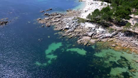 Dive-In-Footage-of-Rocky-Coast-with-Marina-Small-Beach-and-Trees-in-Galicia