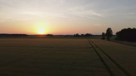 Malerischer-Leuchtend-Orangefarbener-Und-Gelber-Sonnenuntergang-über-Grünem-Ackerland,-Luftaufnahmen