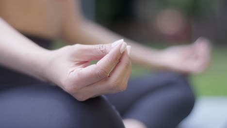 Close-up-shot-of-a-girl's-hands-doing-meditation-on-the-edge-of-a-park-with-radiant-sunlight-and-fresh-air-in-the-morning