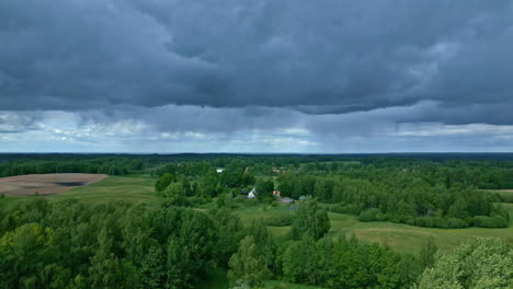 Green-countryside-landscape-and-dark-storm-clouds-above,-aerial-view
