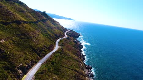 aerial-drone-shot-of-a-Road-on-the-cliff-side-between-the-mountain-and-the-sea