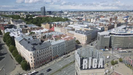 Filmische-Luftaufnahmen-Des-Stadtbildes-Von-Riga-Mit-Dem-Hochfliegenden-Glockenturm-Im-Vordergrund,-Um-Einen-Besseren-Überblick-Zu-Geben,-Lettland,-Europa,-Drohne