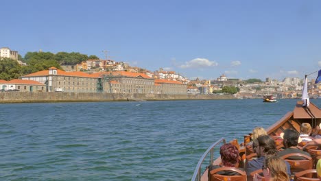 Menschen-Auf-Einem-Touristenboot,-Die-An-Einem-Sonnigen-Tag-Eine-Tour-Auf-Dem-Douro-Fluss-Unternehmen-Und-Das-Porto-Viertel-In-Portugal-Besichtigen