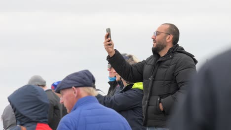 Bearded-man-holds-mobile-phone-recording-vertical-video-at-event