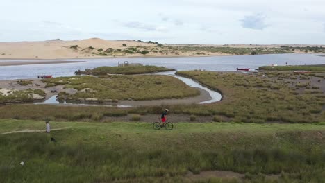 Biker-riding-in-path-beach-of-Valizas,-Rocha