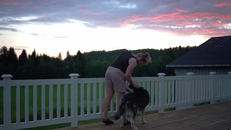 Mann-Und-Haustier-Alaskan-Malamute-Hund-Auf-Der-Veranda-Des-Hauses-Bei-Sonnenuntergang