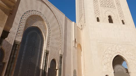 Tilt-down-from-the-horseshoe-archway,-revealing-the-majestic-minaret-of-Hassan-II-Mosque-in-Casablanca,-Morocco