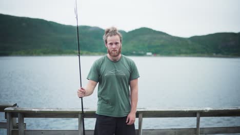 Caucasian-Guy-With-Beard-Holding-A-Fishing-Rod-On-The-Lakeshore