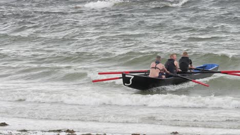 Triumphant-men-beach-currach-boat-rowing-with-traditional-irish-style-on-ladies-beach-ireland