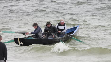 Tracking-shot-follows-three-men-in-currach-boat-paddling-out-to-sea