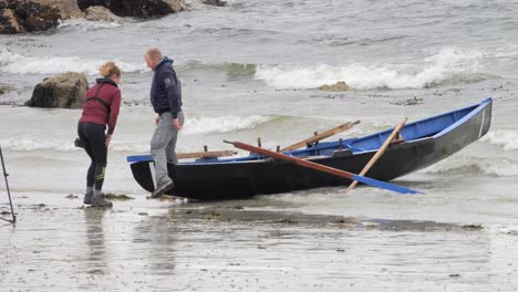 Couple-works-together-to-launch-and-push-currach-boat-into-water-in-ireland