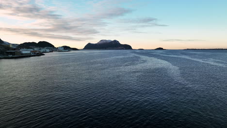Norway-4K-Aerial-of-Ålesund-in-winter-quickly-moving-over-water-with-beatiful-sunset-in-the-background