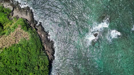 Top-down-aerial-view,-rough-ocean-coastline-with-rocky-cliffs-and-breaking-waves