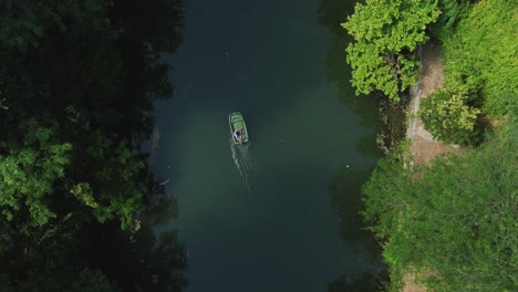 Top-down-aerial-view-of-person-on-motorboat-going-upstream-the-river-"Le-Lez"-in-Southern-France