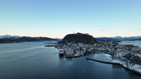 Norway-4K-Aerial-of-Ålesund-in-winter-slowly-descending-looking-back-at-the-harbour-with-beautiful-sunset-in-the-background
