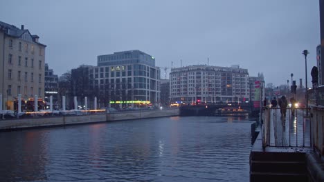 Cinematic-establishing-shot-of-Spree-river-in-Berlin-city-at-twilight,-rainy-day