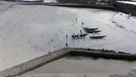 Drone-profile-view-of-people-carrying-currach-boats-towards-waters-edge