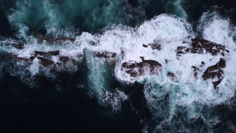 Ocean-Waves-Breaking-of-Partially-Submerged-Rock-Formation,-Aerial-Top-Down-Dolly-In