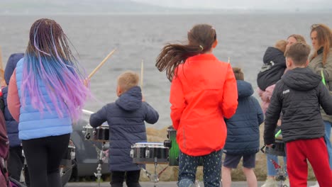 Rearview-of-children-dancing-and-hitting-drums-in-slow-motion-by-ladies-beach