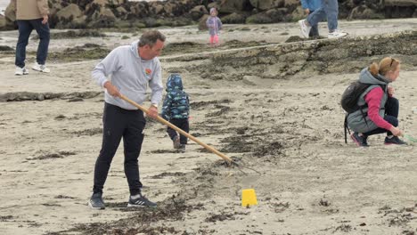 Older-man-rakes-sand-to-clear-and-level-it-at-ladies-beach