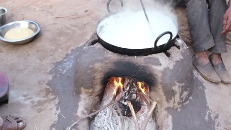 A-cowherd-is-heating-milk-by-placing-a-large-pan-on-the-stove-in-his-village-house