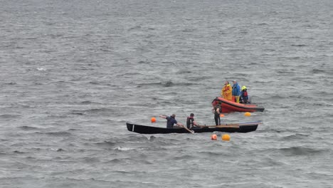 Currach-boat-racers-adjust-clothes-and-stand-for-a-stretch-as-they-round-the-buoy-finish-line
