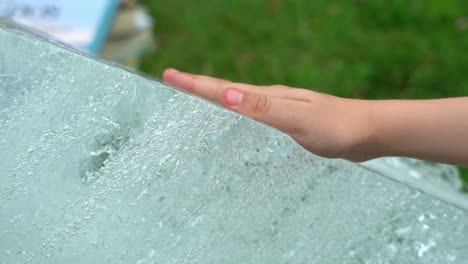 Childrens-hand-is-gently-touching-glacier-ice-block-from-Jostedal-Glacier-outside-museum-in-Fjaerland-Norway---Closeup-of-hand-and-ice-in-slow-motion
