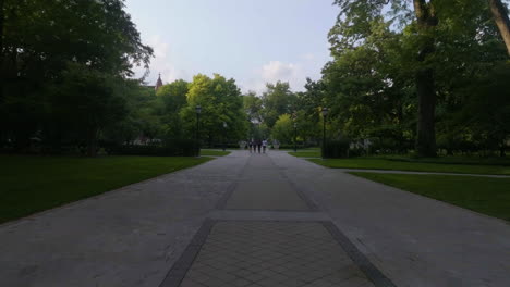 Drone-shot-approaching-students-walking-in-the-parks-of-the-University-of-Chicago,-summer-evening-in-Illinois,-USA