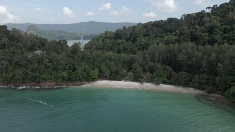 Aerial-retreats-from-small,-picturesque-Sandy-Skulls-Beach,-Malaysia