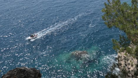 View-over-a-cliff-above-blue-sea-and-boat-passing-by,-Mediterranean