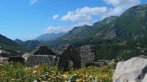 Ruins-of-old-fortress-with-wildflowers-by-the-mountain-range,-reveal-shot