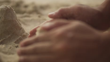 Extreme-Nahaufnahme-Der-Hand-Eines-Mädchens,-Die-Am-Strand-Eine-Sandburg-Formt-–-Sandkunst-Am-Strand