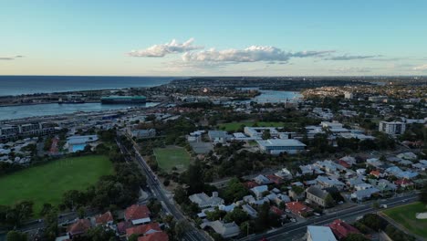 Aerial-flyover-suburb-neighborhood-of-Fremantle-and-Harbor-in-background-at-dusk,-Australia