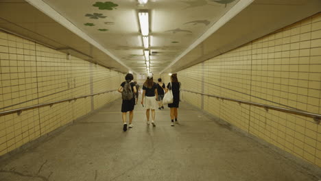 Filmada-Con-Un-Estabilizador,-La-Cámara-Sigue-Suavemente-A-Un-Grupo-De-Personas-Mientras-Caminan-Por-Un-Túnel-En-Hong-Kong.