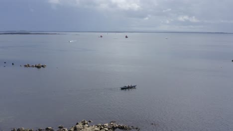 Static-drone-shot-of-currach-boat-traditional-irish-canoe-going-out-into-galway-bay