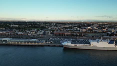 Aerial-forward-flight-over-port-of-Fremantle-with-Dock-with-large-ship-and-Perth-City-in-background
