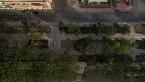 Aerial-view-of-pedestrian-zone-in-green-park-next-to-the-road-in-Malta,-birds-eye-view