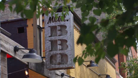 Meat-BBQ-restaurant-sign-in-Lansing,-Michigan-Old-Town-district-with-stable-establishing-shot-in-slow-motion
