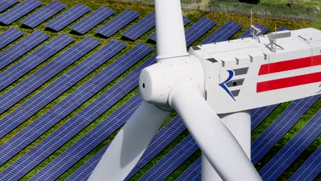Unique-close-up-of-a-wind-turbine-producing-clean-energy-in-the-midst-of-a-solar-farm---strong-parallax-effect-of-solar-panels-moving-in-the-background---telephoto-lens
