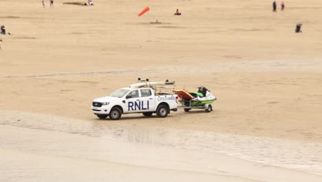 Handaufnahme-Von-RNLI-Rettungsschwimmern,-Die-Am-Strand-Von-Newquay-Patrouillieren-Und-Für-Die-Sicherheit-Der-Surfer-Sorgen