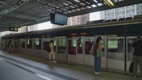 Una-Toma-Estabilizada-Muestra-Un-Tren-Subterráneo-Llegando-A-La-Estación,-Con-Pasajeros-Subiendo-A-Bordo,-Hong-Kong.