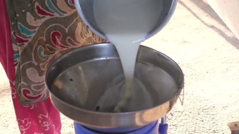 close-up-scene-in-which-a-woman-pours-freshly-churned-Attu-milk-into-a-can