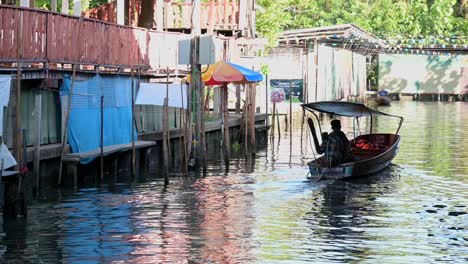 Remando-Un-Bote-De-Madera-En-El-Canal-Del-Mercado-Flotante-Damoen-Saduak,-Tailandia