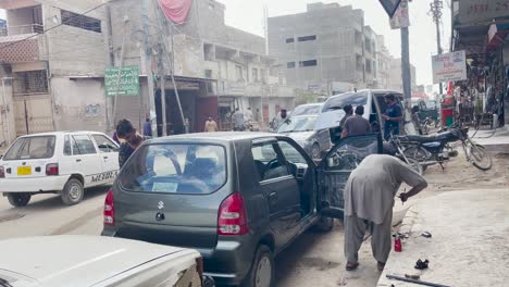 Toma-De-Mecánicos-Reparando-Un-Automóvil-En-El-Mercado-De-Reparación-De-Automóviles,-Saddar-En-Karachi,-Pakistán-Durante-El-Día