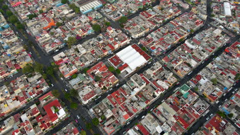 Vuelo-Aéreo-Sobre-Los-Edificios-De-Viviendas-Del-Barrio-De-Salvador-Diaz-Con-Automóviles-Circulando-En-El-Tráfico-Por-Carretera