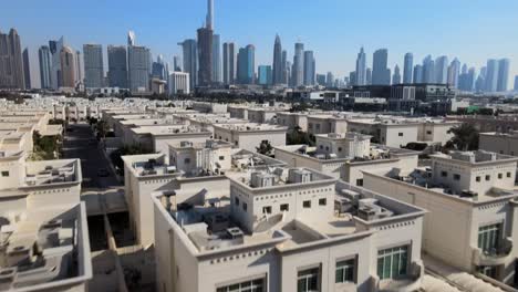 Toma-Aérea-Inclinada-Hacia-Arriba-Que-Muestra-A-Un-Hombre-Caminando-En-La-Azotea-Disfrutando-De-Las-Vistas-De-La-Ciudad-De-Dubai-Con-El-Horizonte,-Emiratos-Árabes-Unidos