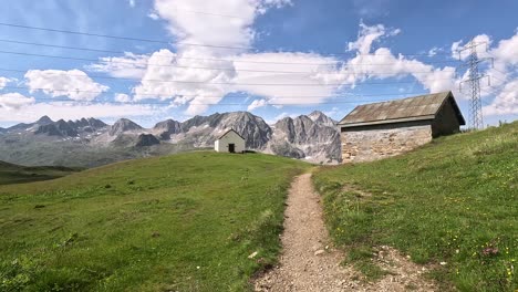 Eine-Weiße-Kapelle-Und-Eine-Berghütte-Nähern-Sich-Einer-Grünen-Sommerwiese